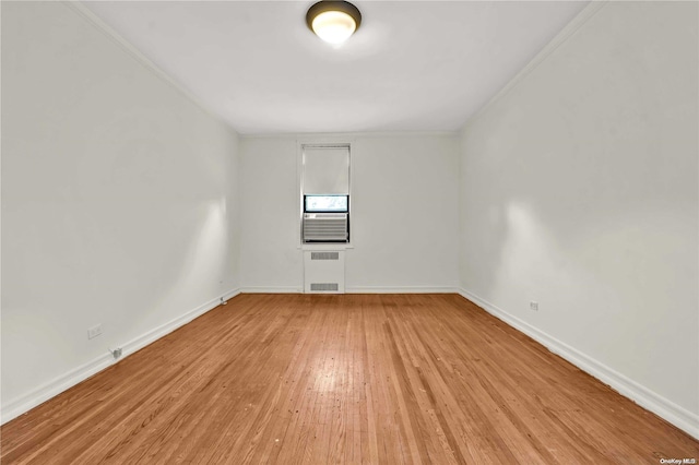 spare room featuring ornamental molding, radiator heating unit, and light wood-type flooring