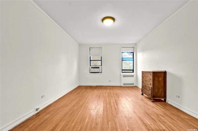 unfurnished room with cooling unit, radiator, and light wood-type flooring