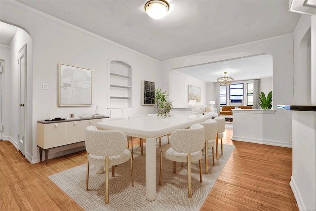 dining area featuring ornamental molding, light wood-type flooring, and built in shelves