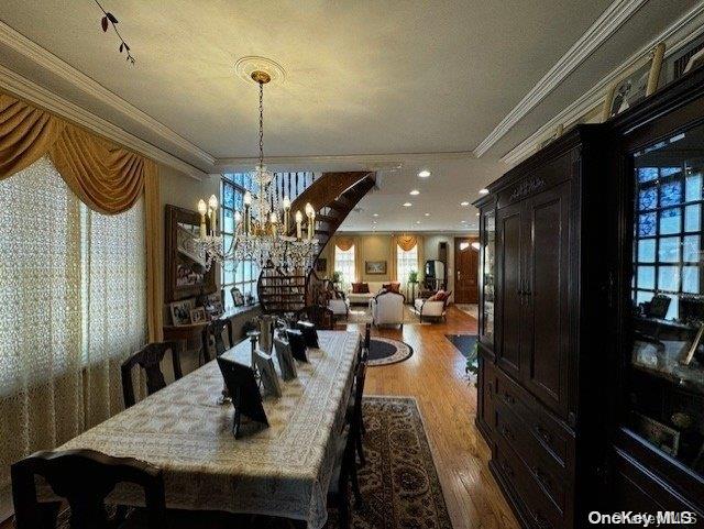 dining space with crown molding, a chandelier, a textured ceiling, and hardwood / wood-style flooring