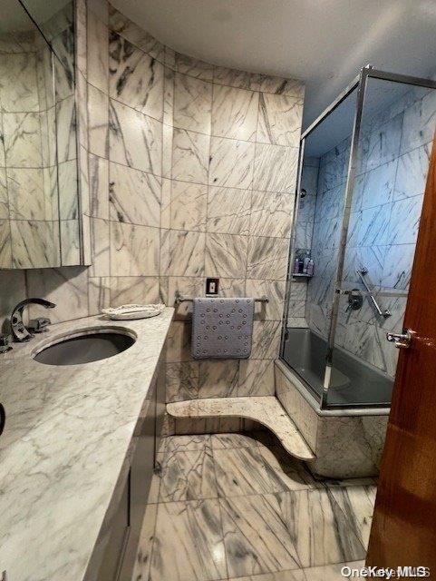 bathroom featuring vanity, walk in shower, and tile walls