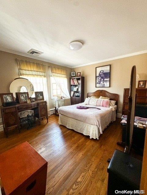 bedroom with dark wood-type flooring and ornamental molding