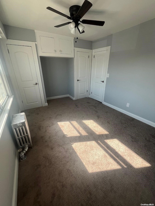 unfurnished bedroom featuring ceiling fan and dark carpet