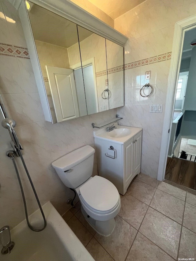 bathroom featuring toilet, vanity, tile patterned floors, and tile walls