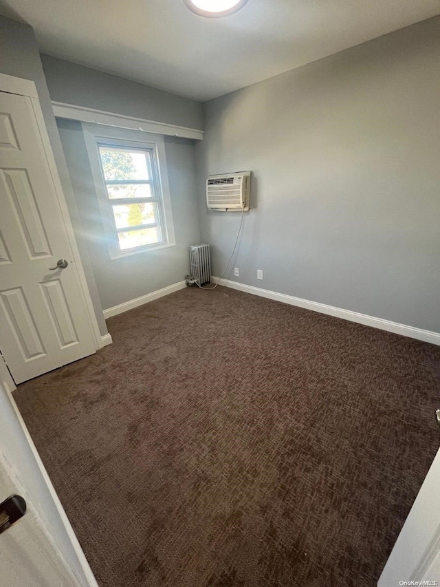 carpeted empty room with a wall unit AC and radiator