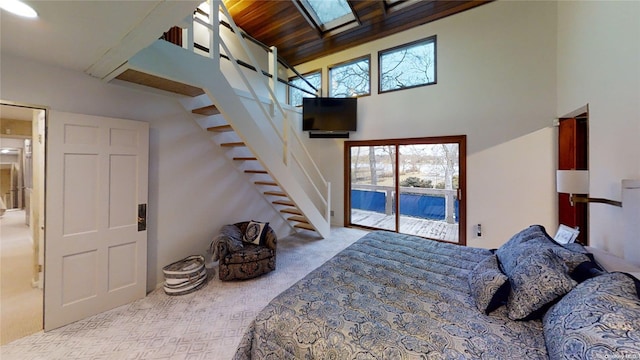 carpeted bedroom featuring access to exterior, a high ceiling, multiple windows, and wooden ceiling