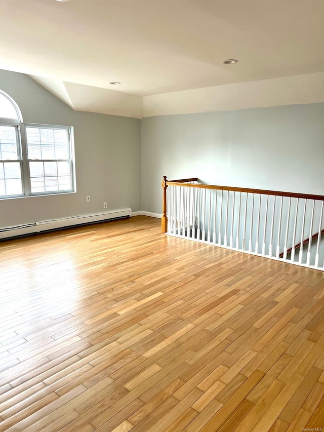 empty room featuring baseboard heating and light hardwood / wood-style floors