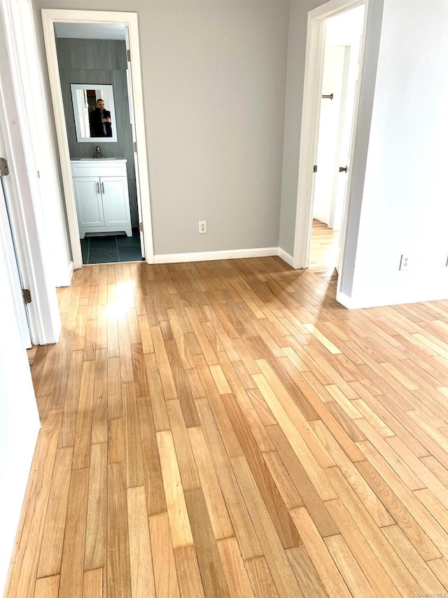 unfurnished room with sink and light hardwood / wood-style flooring