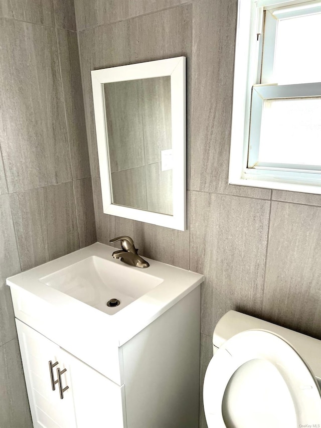 bathroom with vanity, tile walls, and toilet