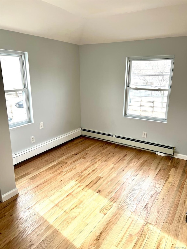 unfurnished room featuring a baseboard radiator and light hardwood / wood-style flooring