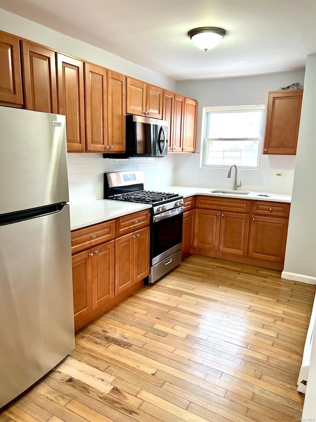 kitchen featuring sink, decorative backsplash, light hardwood / wood-style flooring, and appliances with stainless steel finishes