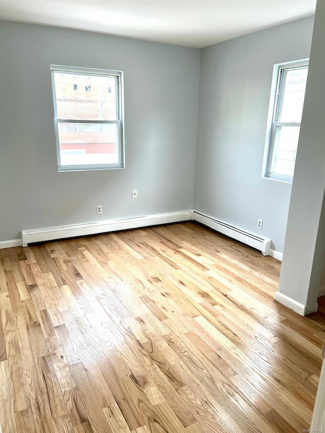 unfurnished room featuring baseboard heating and light hardwood / wood-style flooring