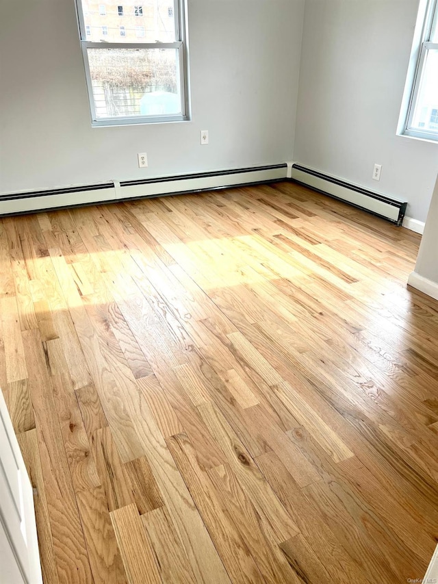 spare room featuring a baseboard heating unit and light wood-type flooring