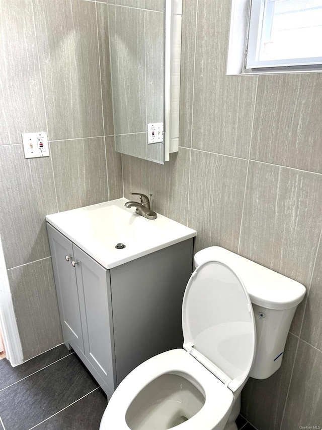 bathroom featuring tile patterned flooring, vanity, tile walls, and toilet