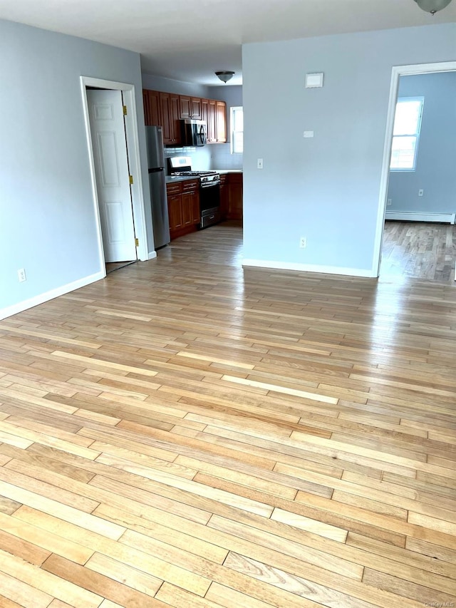 unfurnished living room with baseboard heating and light hardwood / wood-style floors