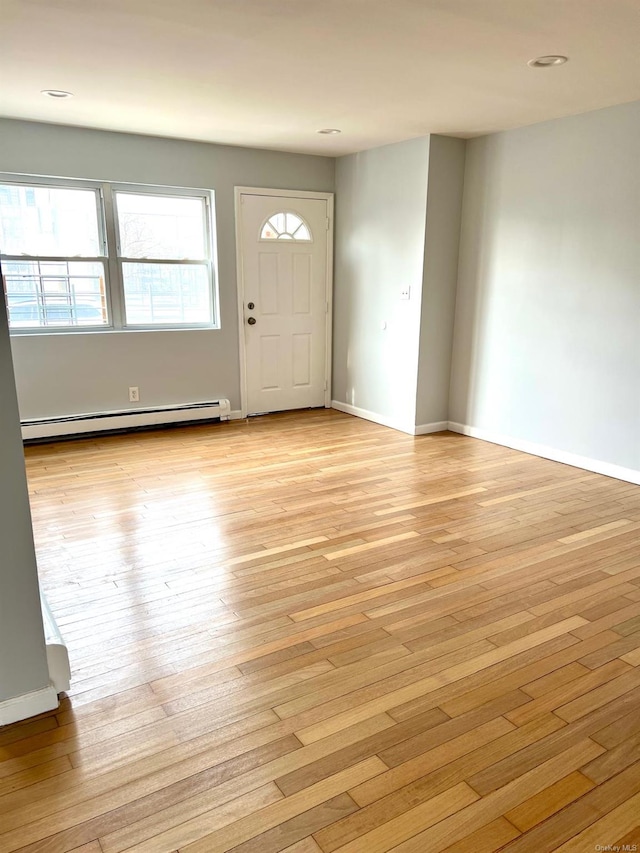 entrance foyer with a baseboard heating unit and light hardwood / wood-style flooring