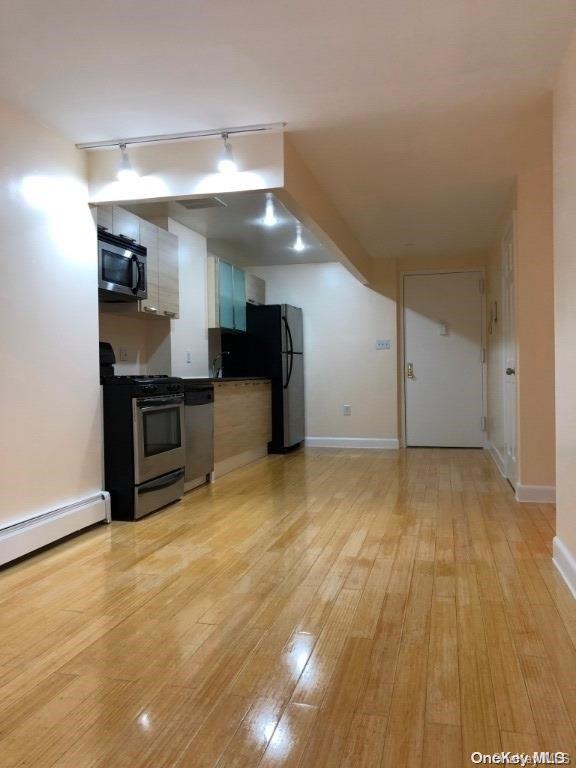 interior space featuring rail lighting, stainless steel appliances, light hardwood / wood-style flooring, and baseboard heating