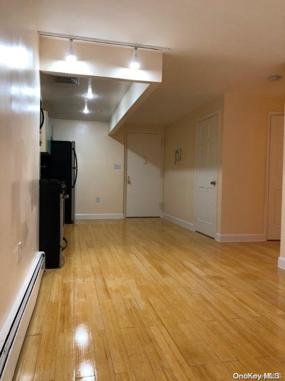 interior space with rail lighting, light wood-type flooring, and a baseboard heating unit