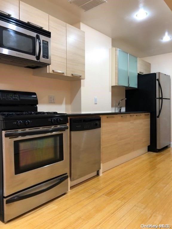 kitchen featuring light brown cabinetry, stainless steel appliances, and light hardwood / wood-style floors