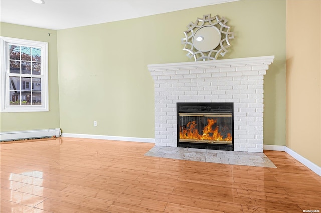 unfurnished living room with a brick fireplace, light hardwood / wood-style floors, and a baseboard heating unit