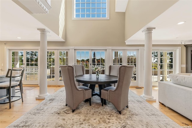 dining space with decorative columns, a healthy amount of sunlight, light wood-type flooring, and french doors