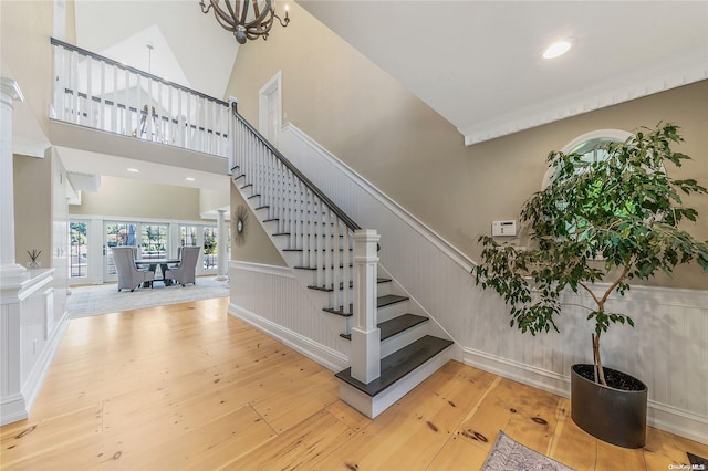 stairway featuring wood-type flooring, a high ceiling, and a chandelier