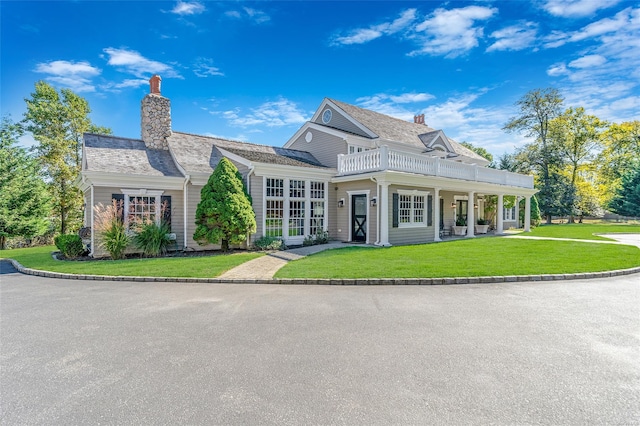 view of front of home with a balcony and a front lawn