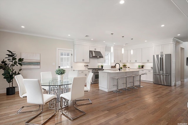 dining area with wood-type flooring, crown molding, and sink