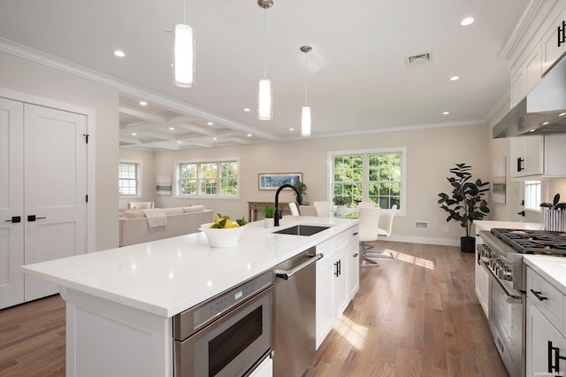 kitchen featuring white cabinets, appliances with stainless steel finishes, a center island with sink, and sink