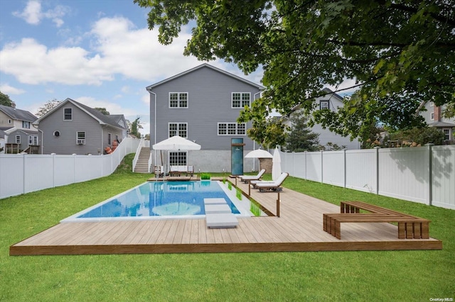 view of swimming pool with a wooden deck, a diving board, and a yard