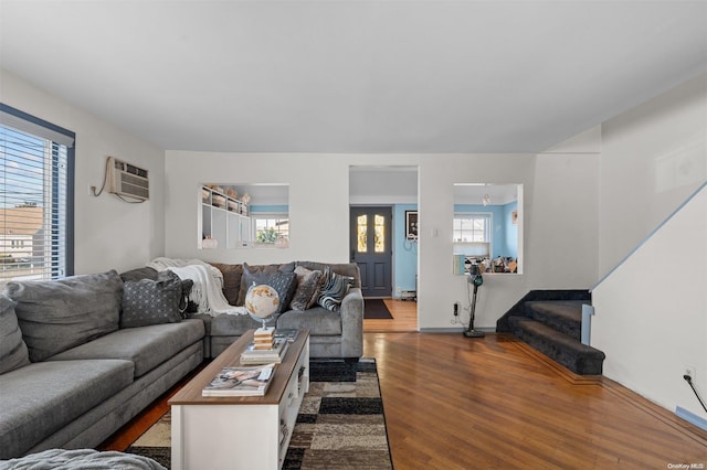 living room featuring an AC wall unit, hardwood / wood-style floors, and a healthy amount of sunlight