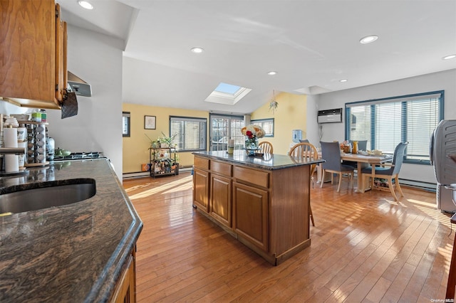 kitchen featuring a wall mounted AC, a center island, a healthy amount of sunlight, and light wood-type flooring