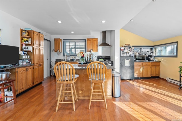 kitchen featuring wood-type flooring, wall chimney range hood, stainless steel appliances, and vaulted ceiling