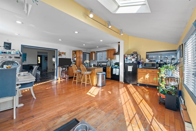 interior space with light wood-type flooring and vaulted ceiling with skylight