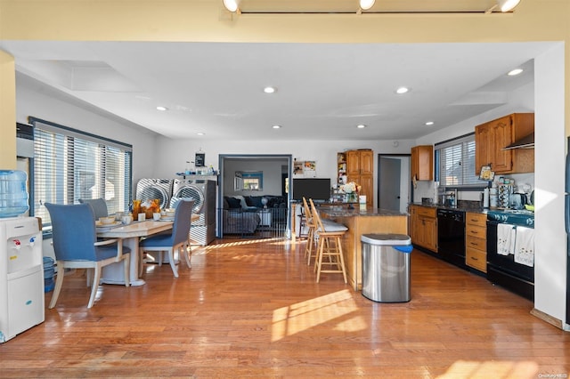 kitchen with black appliances, light wood-type flooring, and a wealth of natural light