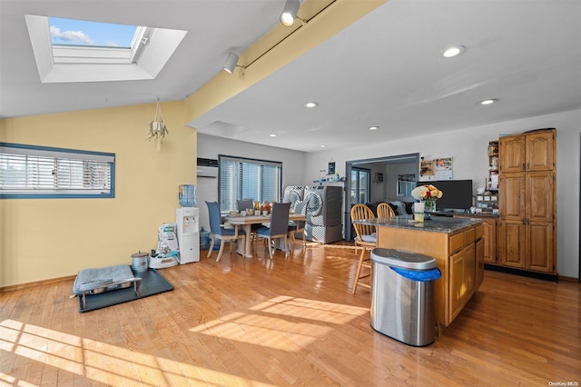 kitchen with a wall mounted air conditioner, a center island, lofted ceiling with skylight, light wood-type flooring, and a breakfast bar area