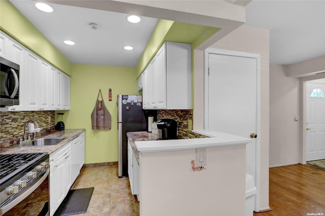 kitchen with backsplash, stainless steel appliances, white cabinetry, and sink