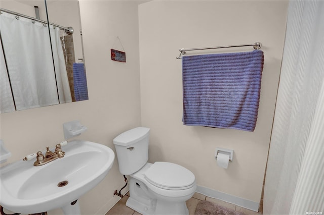 bathroom featuring toilet, curtained shower, sink, and tile patterned flooring