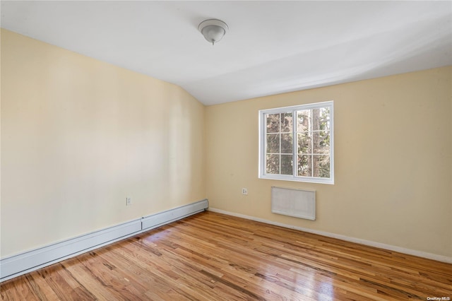 unfurnished room with light hardwood / wood-style floors, lofted ceiling, and a baseboard heating unit