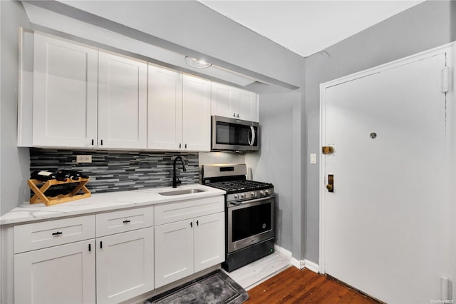 kitchen featuring white cabinetry, sink, light stone counters, dark hardwood / wood-style flooring, and appliances with stainless steel finishes