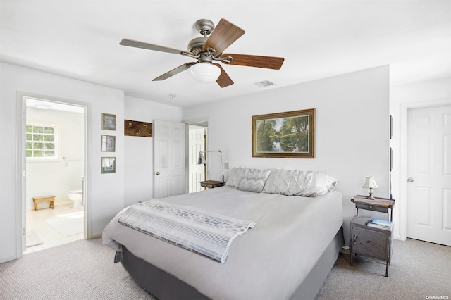 bedroom with ceiling fan, light carpet, and connected bathroom