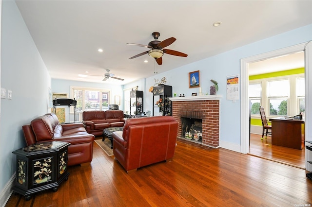 living room with dark hardwood / wood-style flooring, a brick fireplace, and ceiling fan