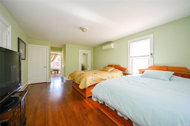 bedroom with a wall mounted air conditioner and dark wood-type flooring