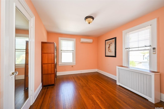 spare room with a wall mounted AC, dark hardwood / wood-style floors, and radiator