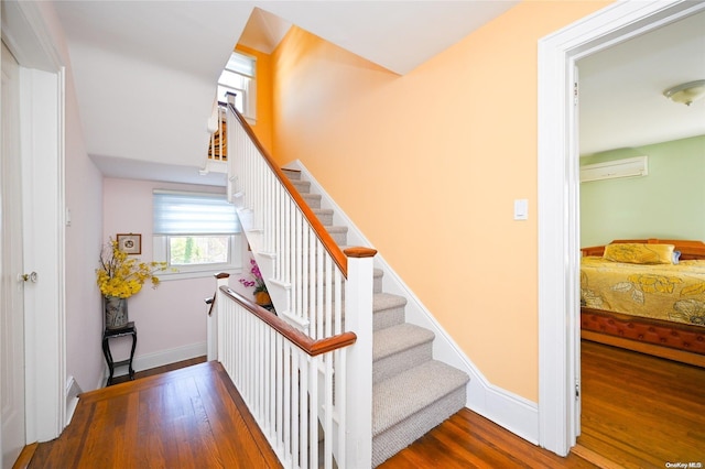 stairway with a wall mounted AC and hardwood / wood-style floors