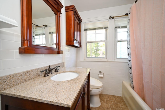 full bathroom featuring vanity, shower / bath combination with curtain, toilet, and tile walls