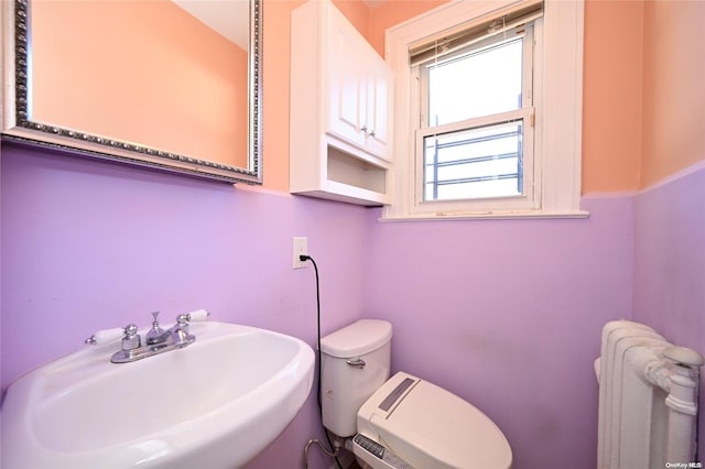 bathroom featuring radiator heating unit, toilet, and sink