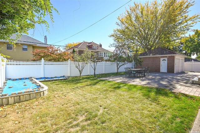 view of yard featuring an outbuilding, a patio, and a garage