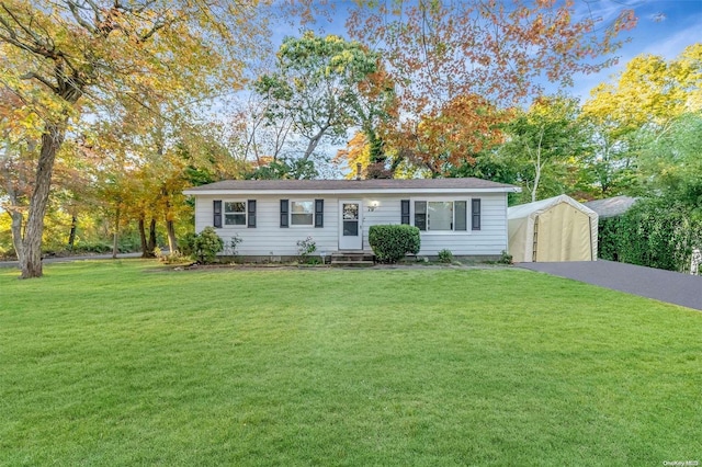 single story home featuring a carport, a front lawn, and an outdoor structure