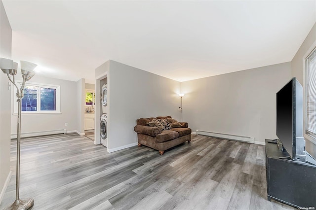 living area with stacked washer and dryer, hardwood / wood-style floors, and a baseboard heating unit